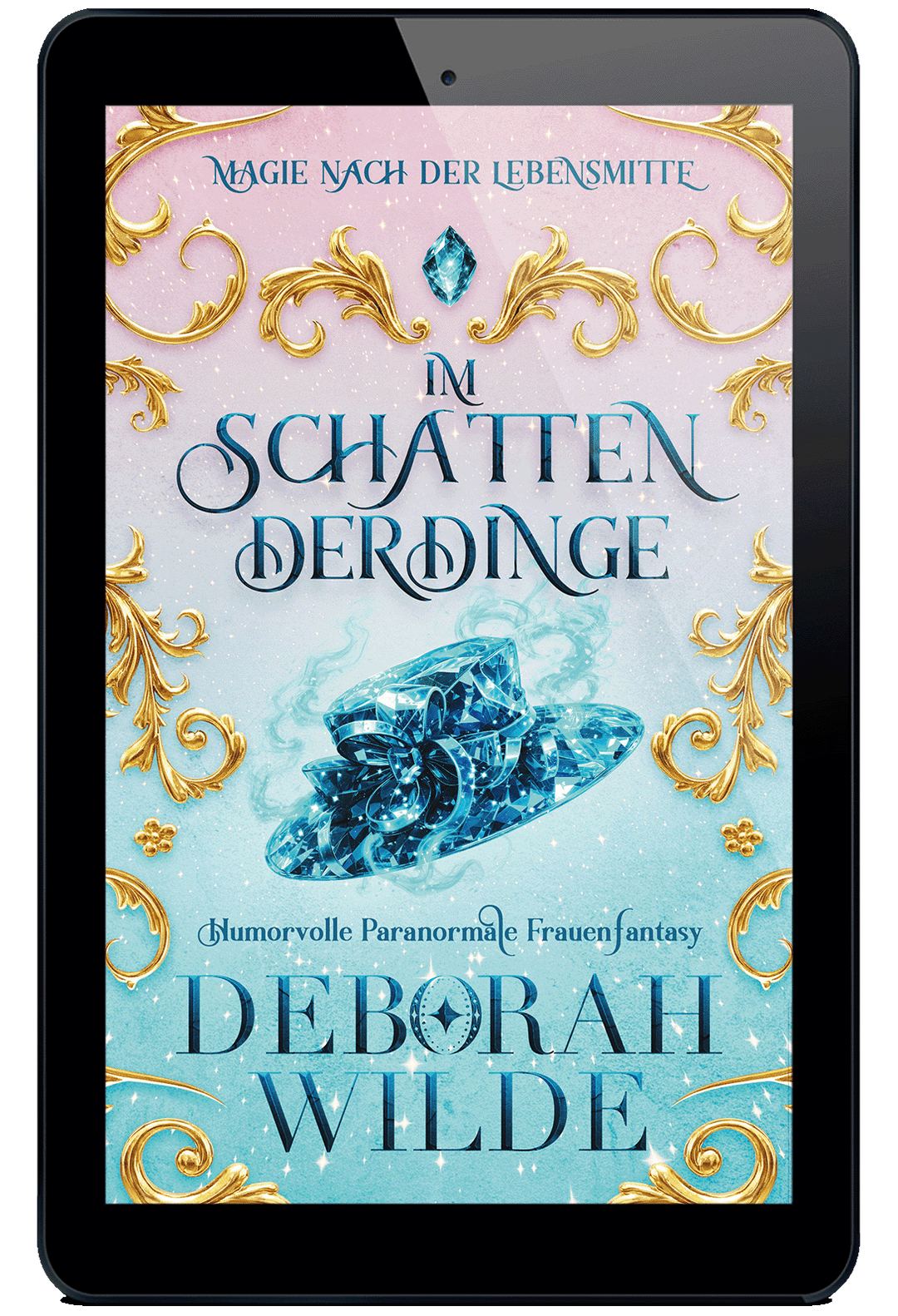 E-Book-Cover für ‚Im Schatten der Dinge‘ von Deborah Wilde auf einem Tablet. Das Design zeigt einen hellblauen, glitzernden Hintergrund mit goldenen Ornamenten und einem rauchenden, funkelnden blauen Hut im Zentrum.
